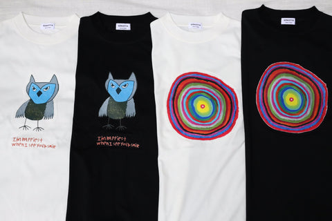 白い布の上に並べたアートTシャツ4枚（フクロウとまる、白と黒）